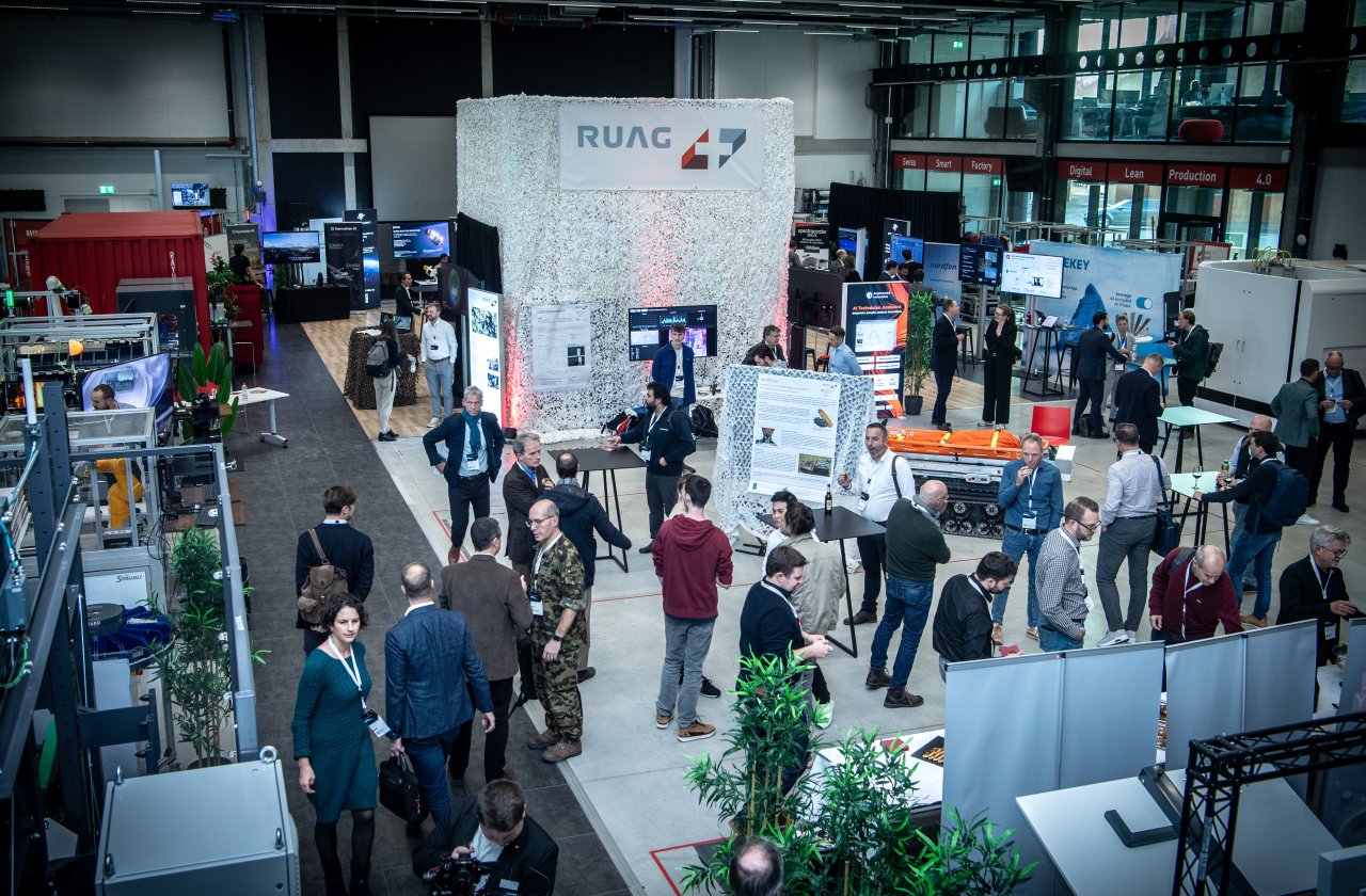 Eine Messe mit vielen Ständen und Besuchern ist ersichtlich.