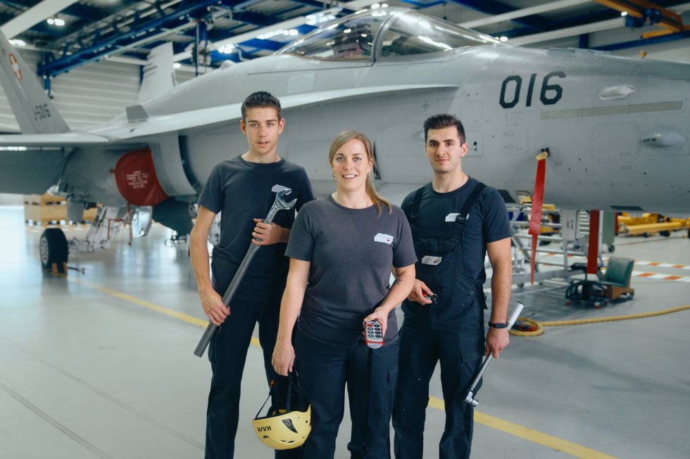 Drei Mechaniker in einer Flugzeughalle.