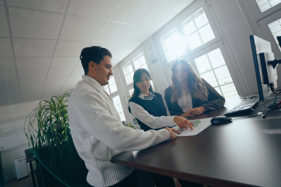 Drei Personen besprechen etwas zusammen im Büro.